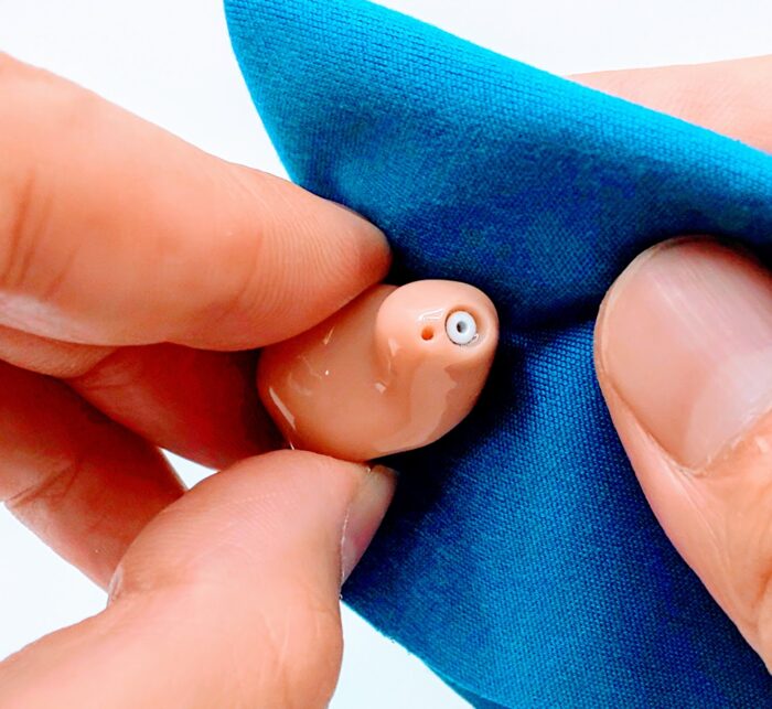 耳あな型補聴器を乾いた布でふく様子